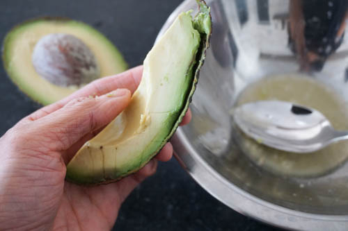 peeling quartered avocado